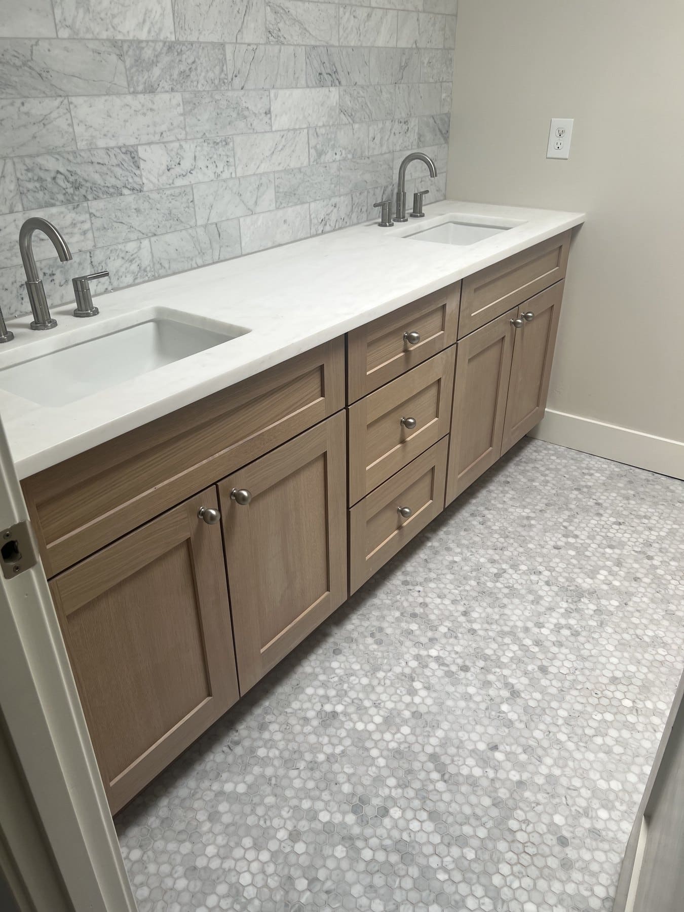 Double-sink vanity with a marble subway backsplash and hexagon-tile floor
