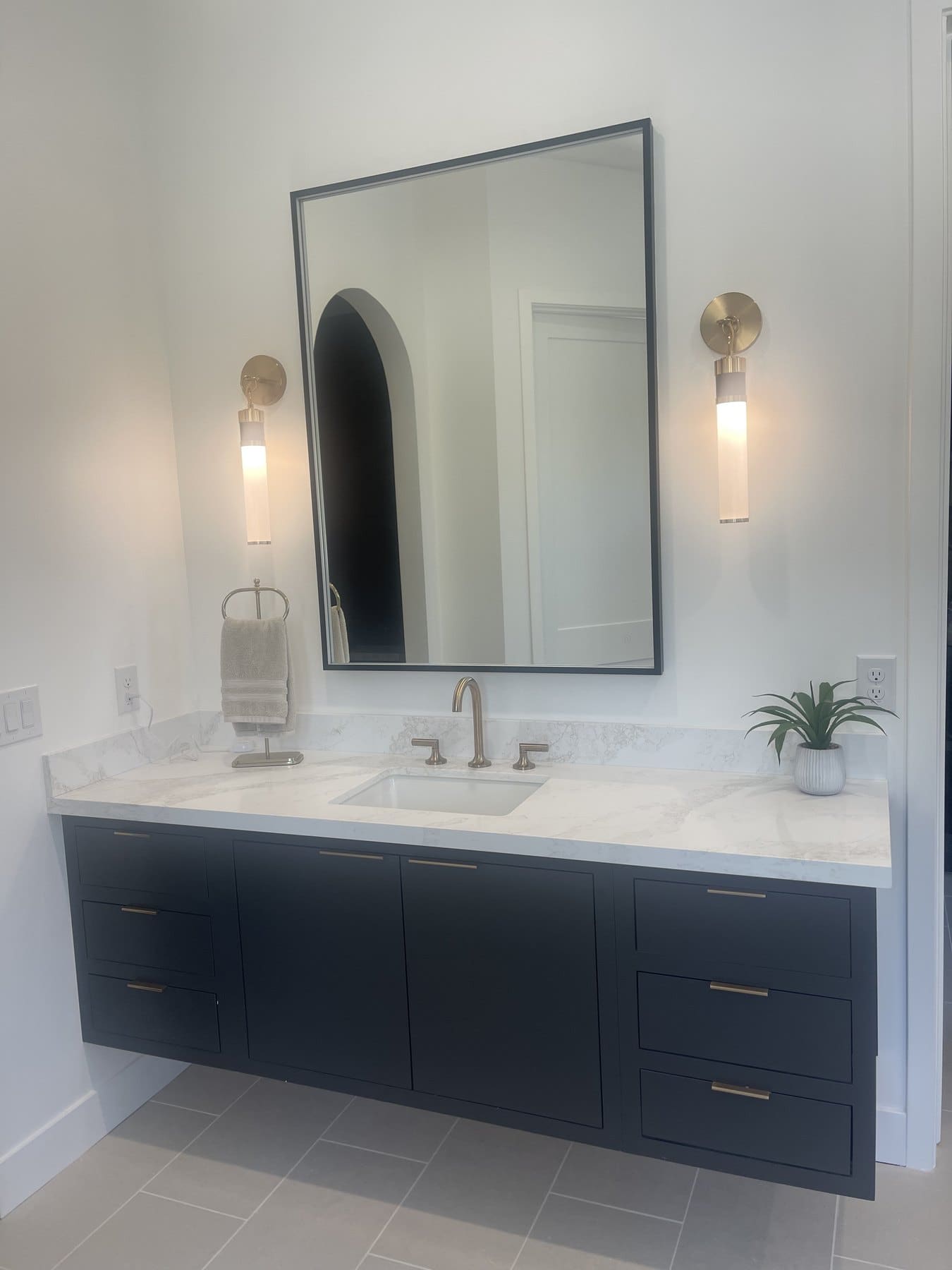 Bathroom vanity with dark cabinetry and wall sconces