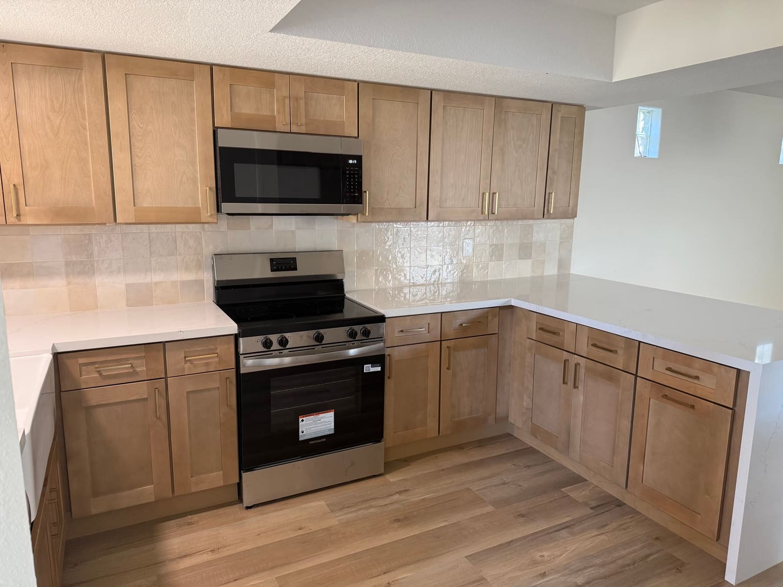 Newly finished natural-wood shaker kitchen with stainless range, tile backsplash, and quartz countertops