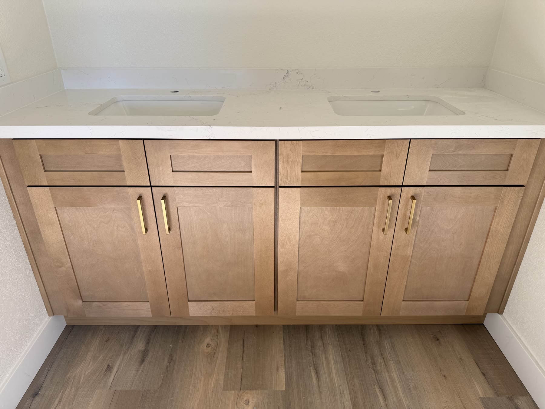 Double-sink bathroom vanity in natural wood with brushed-gold hardware and quartz top
