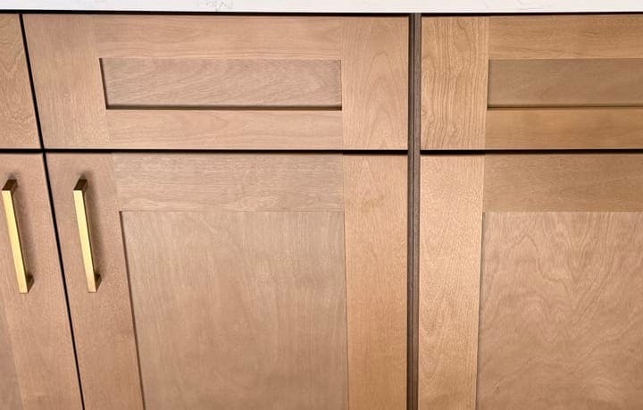 Brushed-gold bar pulls on natural-wood shaker cabinet doors