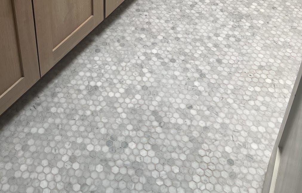 Marble hexagon mosaic floor running to the toe kick of the vanity